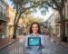 Vibrant scene of DeLand downtown with business owner holding tablet displaying digital growth analytics, blending local charm and modern marketing.