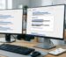 Modern office desk with two monitors showing Google search results and a People Also Ask box, smartphone with Google Maps beside keyboard, emphasizing local SEO and AI-driven solutions.