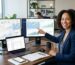 AI consultant at a modern desk with dual monitors displaying local SEO dashboards and maps, pointing to a chart while a laptop shows Google My Business listings in a bright office.