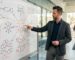 Digital marketing strategist analyzing go-to-market strategy diagrams on whiteboard