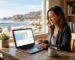Smiling small business owner working at a wooden desk in a sunlit Ventura office, viewing an AI local SEO dashboard on a laptop with maps and graphs, Ventura Pier visible through the window.
