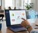 Modern ecommerce workspace with a laptop displaying SEOLocal dashboard, Shopify, WooCommerce, and Magento integration icons, a translucent holographic AI agent icon hovering, and a human hand touching the screen to deploy an agent, set in a bright airy office with subtle technology accents.