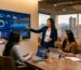 Marketing team collaborating around a large screen with SEO dashboards in a Denver office, city skyline visible through windows.